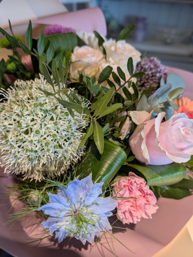 pink and purple handtied flower bouquet in a gift bag