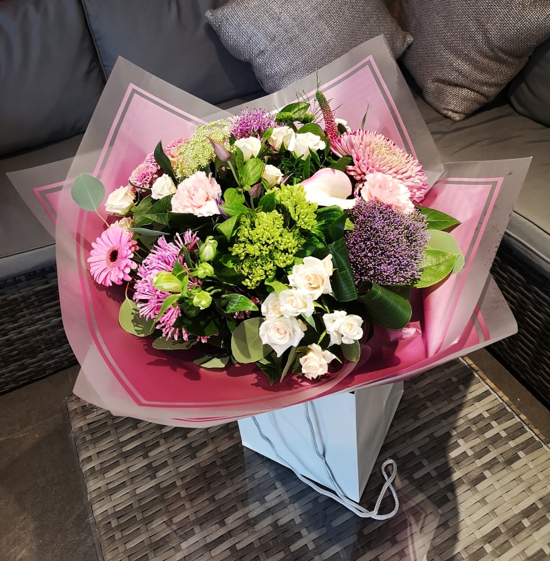 pink and purple handtied flower bouquet in a gift bag