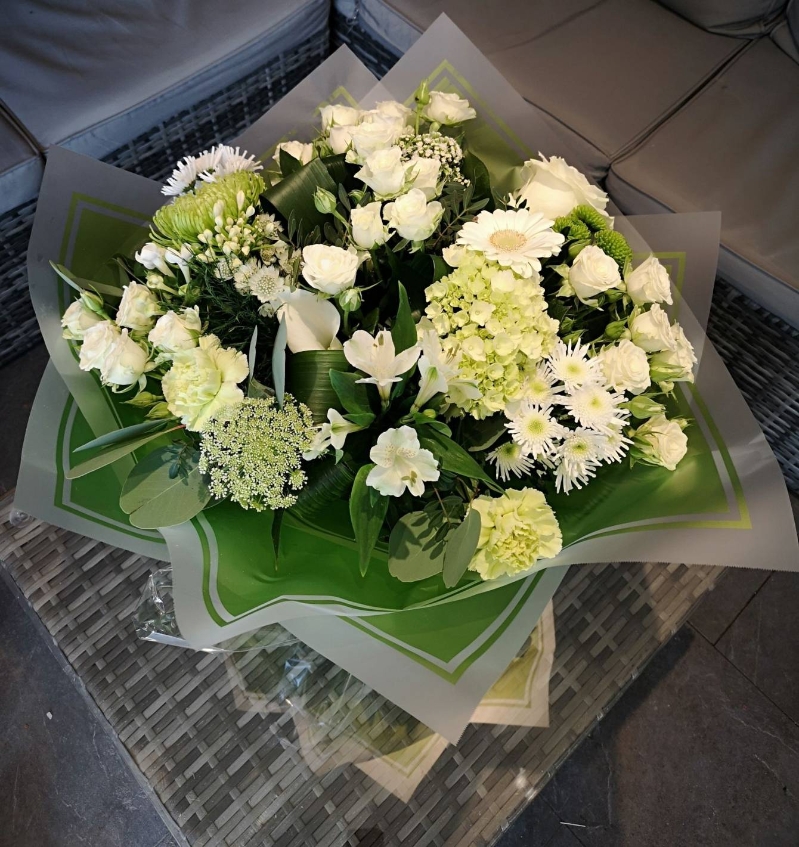 bright handtied flower bouquet gift wrapped aqua pack of water, held by our local florist