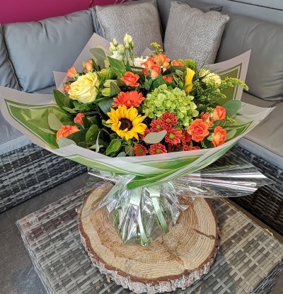 bright handtied flower bouquet gift wrapped aqua pack of water, held by our local florist