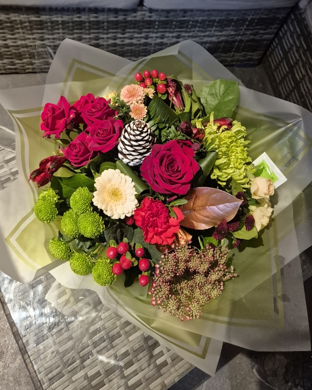 Red and green flower handtied bouquet in a gift bag