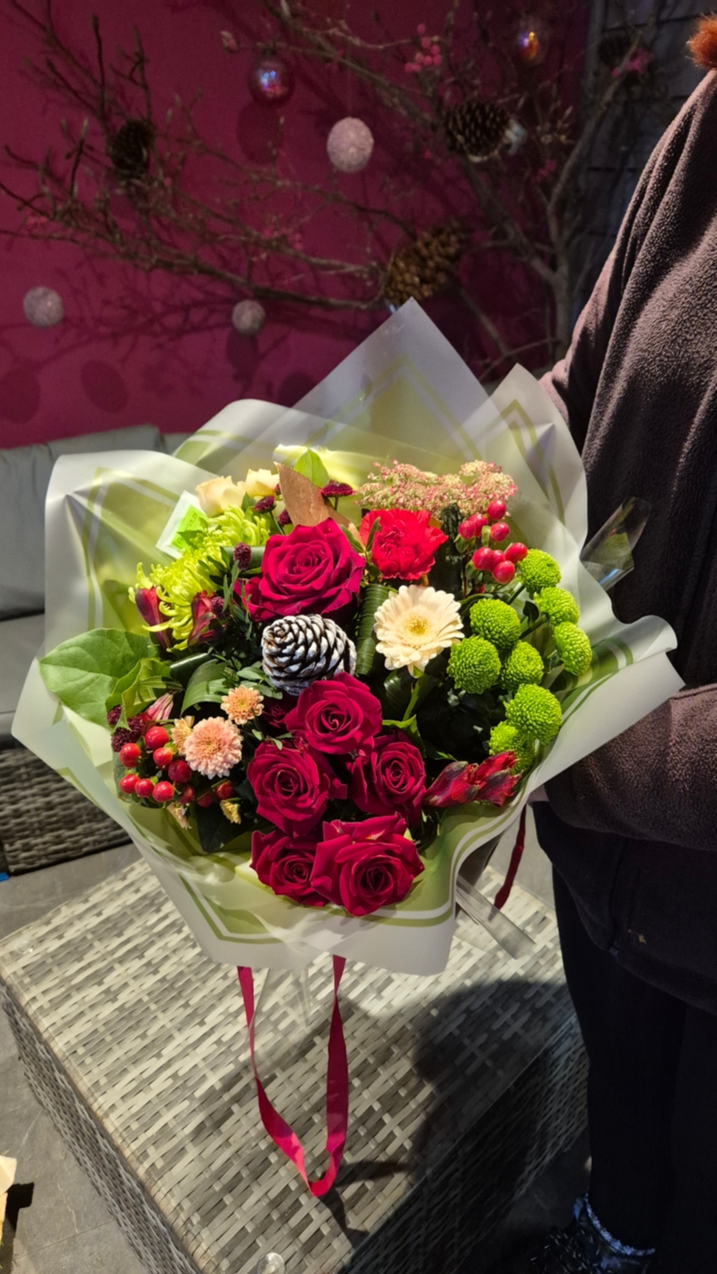 Red and green flower handtied bouquet in a gift bag
