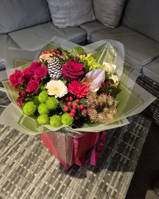 Red and green flower handtied bouquet in a gift bag