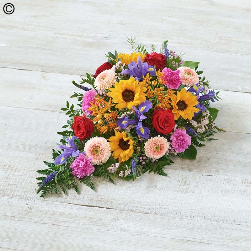 vibrant mixed flower and foliage singled ended funeral coffin spray