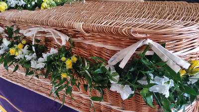 Country style foliage coffin garland including spray roses and fragranced flowers threaded around casket 