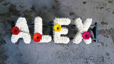 Simple white based chrysanthemum letter funeral tribute with flower and grass linking each letter