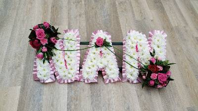 White based chrysanthemum mum letter funeral tribute with flower spray and pink ribbon edge