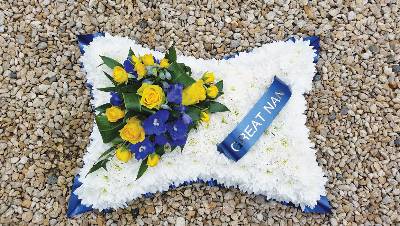 White chrysanthemum based cushion funeral flower tribute with yellow and blue 