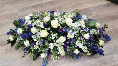 White rose and blue delphinium flower and foliage double ended funeral coffin spray 