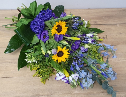 Hand-tied funeral sheaf with pale blue delphinium, scented phlox, bright yellow sunflowers and solidago, pretty purple lisianthus, velvet anemone and scented hyacinth.