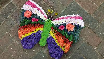 Vibrant flower and foliage butterfly funeral tribute