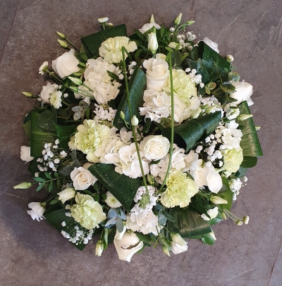 A timeless posy with ivory roses, soft green carnations, and delicate hydrangeas. Accented with gypsophila and glossy tropical foliage.