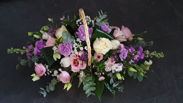 A trug style basket with lilac-scented stocks, ivory roses, white veronica, rose pink lisianthus and white accents.