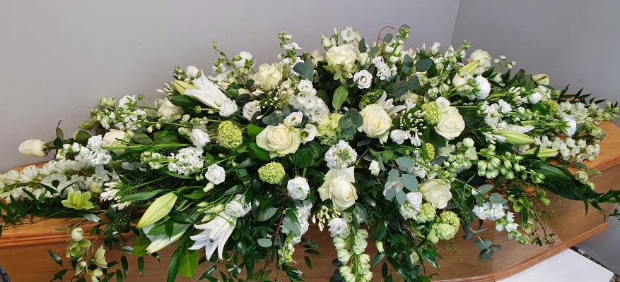 This double-ended spray features a combination of white roses, white lilies, white stock, white lisianthus, white delphinium and lush greenery.