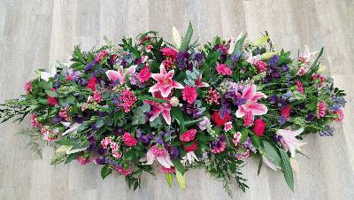 Pink, cerise and purple flower and foliage double ended funeral coffin spray with lilies