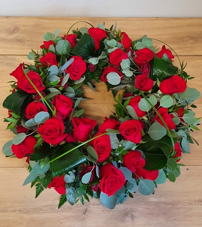 Funeral wreath with rich red roses and mixed foliage