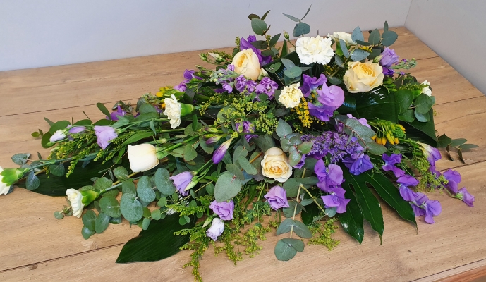 A pretty lilac and lemon single ended spray with pale lemon roses and carnations, lilac lisianthus, yellow solidago and a mix of scented lilac blooms.