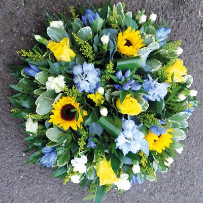 Yellow sunflower and blue delphinium funeral tribute flower and foliage posy