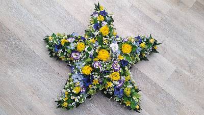 Yellow and purple flower and foliage star shaped funeral tribute 