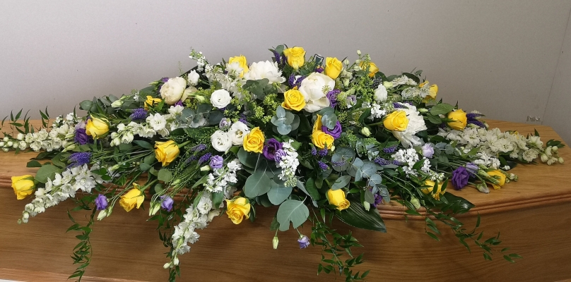Yellow and white coffin spray with soft touches of purple and lush greenery