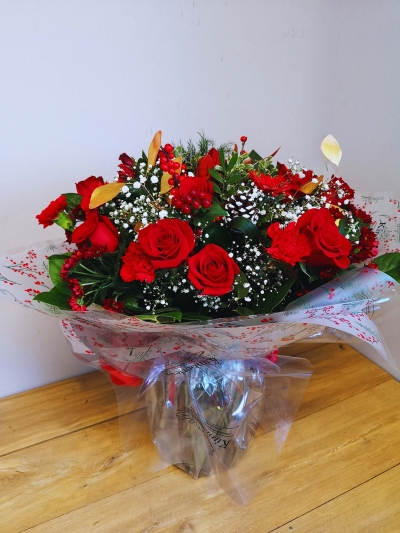 Festive chritsmas red rose flower handtied bouquet in a vase