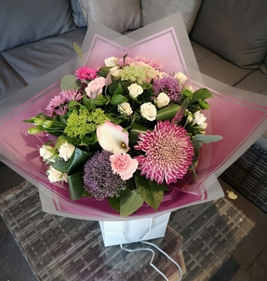 pink and purple handtied flower bouquet in a gift bag