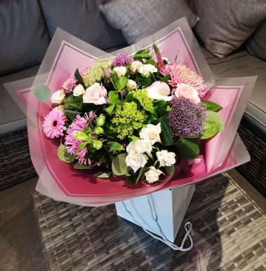 pink and purple handtied flower bouquet in a gift bag