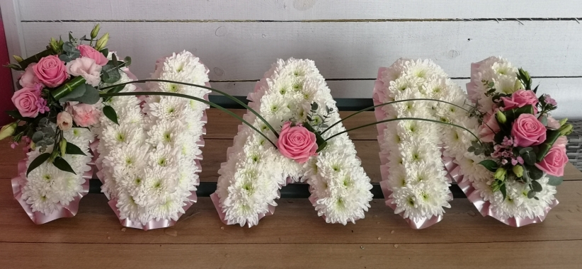 White based chrysanthemum mum letter funeral tribute with flower spray and pink ribbon edge