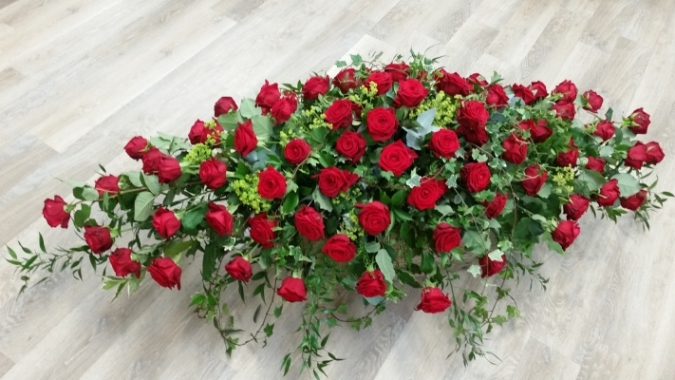 Classic red rose flower and foliage double ended funeral coffin spray with trails of soft ruscus and ivy