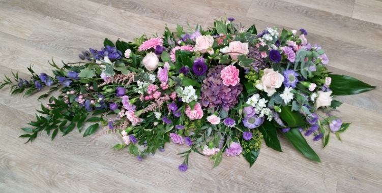 Country style pink, purple and lilac flower and foliage single ended funeral coffin spray 