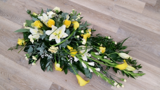 Yellow and white flower and foliage single ended funeral coffin spray with roses and lilies 