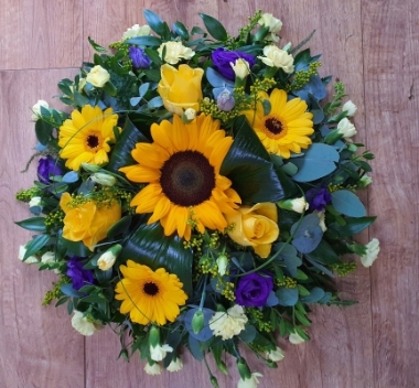  A bright and sunny round posy of yellow germini, sunflower and roses with contrasting purple lisianthus.