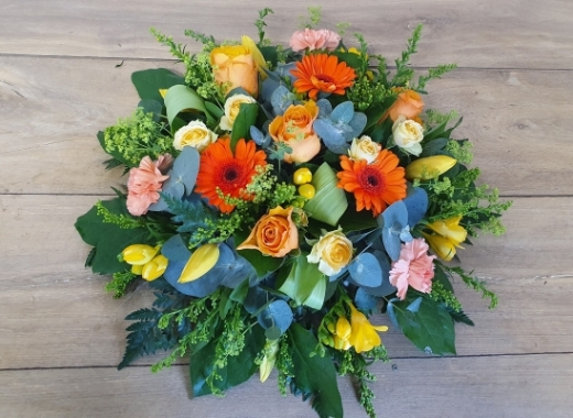 Seasonal spring orange flower and foliage posy funeral tribute