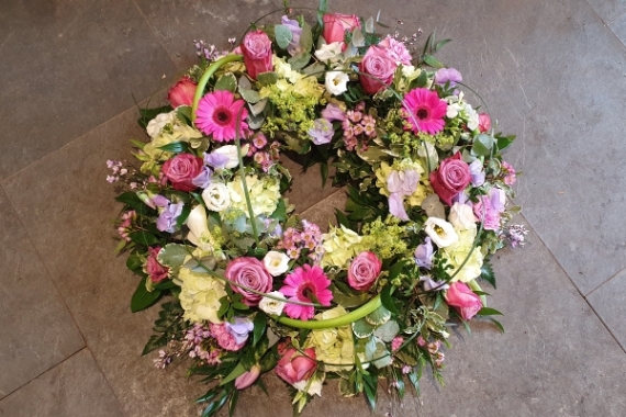 Wreath funeral tribute with roses and lisianthus, soft lime hydrangea and pretty germini with a hint of lilac and whites.