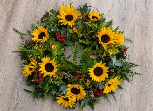 Wild yellow flower and foliage funeral tribute wreath with sunflower and berries 