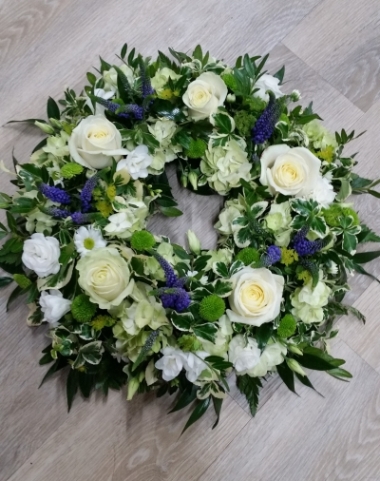 White and purple flower and foliage funeral tribute wreath with roses and veronica