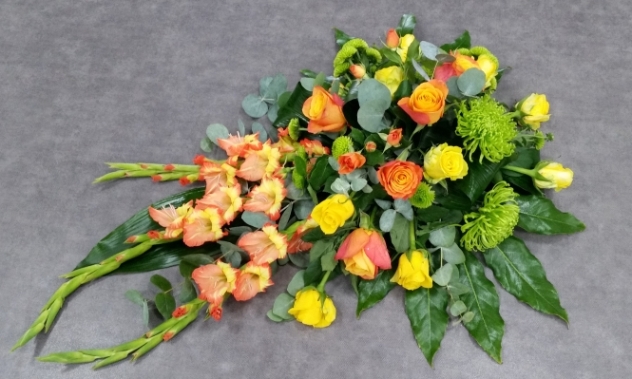 A warm, autumnal single ended spray with radiant gladioli, vibrant orange and yellow roses, and zesty lime blooms, beautifully complemented by glossy, lush foliage