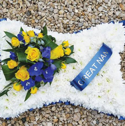 White chrysanthemum based cushion funeral flower tribute with yellow and blue 