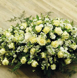 White and ivory flower and foliage double ended funeral coffin spray including roses and delphinium 