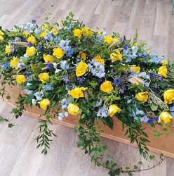 Country yellow rose and blue delphinium flower double ended funeral coffin spray, with foliage including wheat and trails