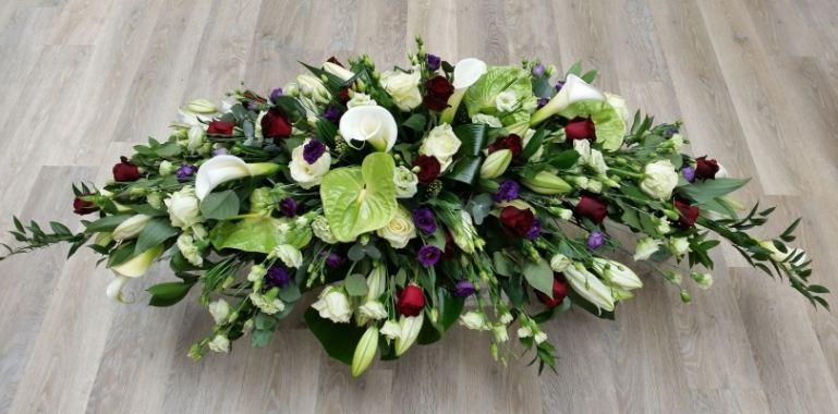 Eternal Harmony coffin spray, with white roses, calla lilies, red roses and velvety purple lisianthus