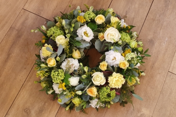 Funeral wreath with soft lemon and white flowers, including roses, lisianthus and zesty lime viburnham.