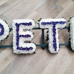 White based chrysanthemum letter funeral tribute with line of coloured flowers in the centre, can be edged with coloured ribbon or foliage