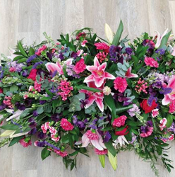 Pink, cerise and purple flower and foliage double ended funeral coffin spray with lilies