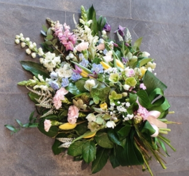 Hand-tied funeral sheaf with garden delphinium, scented stocks and antirrhinum, scented hyacinth, glorious hellebore and star clematis and various country garden flowers.