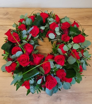 Funeral wreath with rich red roses and mixed foliage