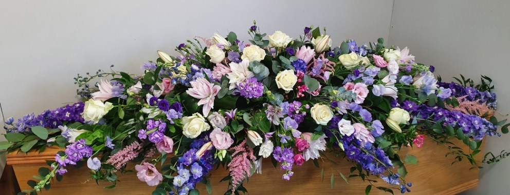 This Tranquil Beauty double-ended spray features a lovely blend of white roses, pink lilies, purple lisianthus, delphiniums, and lush greenery.