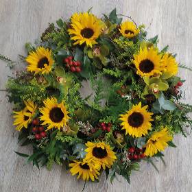 Wild yellow flower and foliage funeral tribute wreath with sunflower and berries 