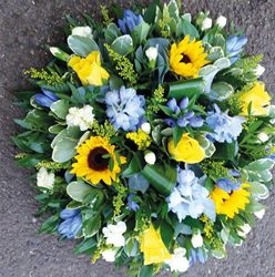 Yellow sunflower and blue delphinium funeral tribute flower and foliage posy