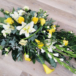 Yellow and white flower and foliage single ended funeral coffin spray with roses and lilies 
